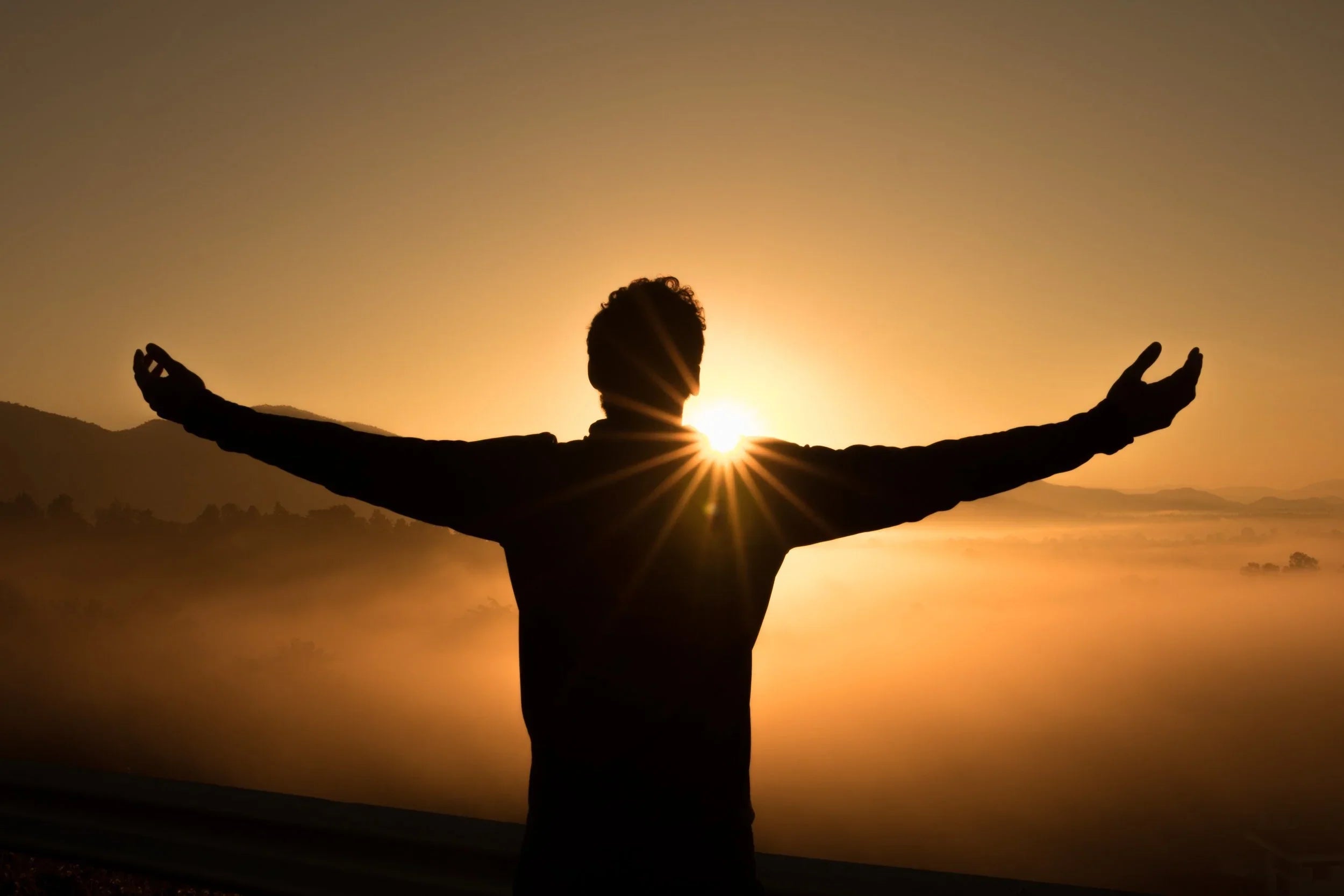 Image of man with open arms with sun